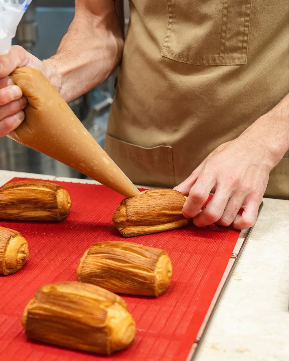 Le mani del pasticcere farciscono una sfoglia dorata nel laboratorio di Matrice